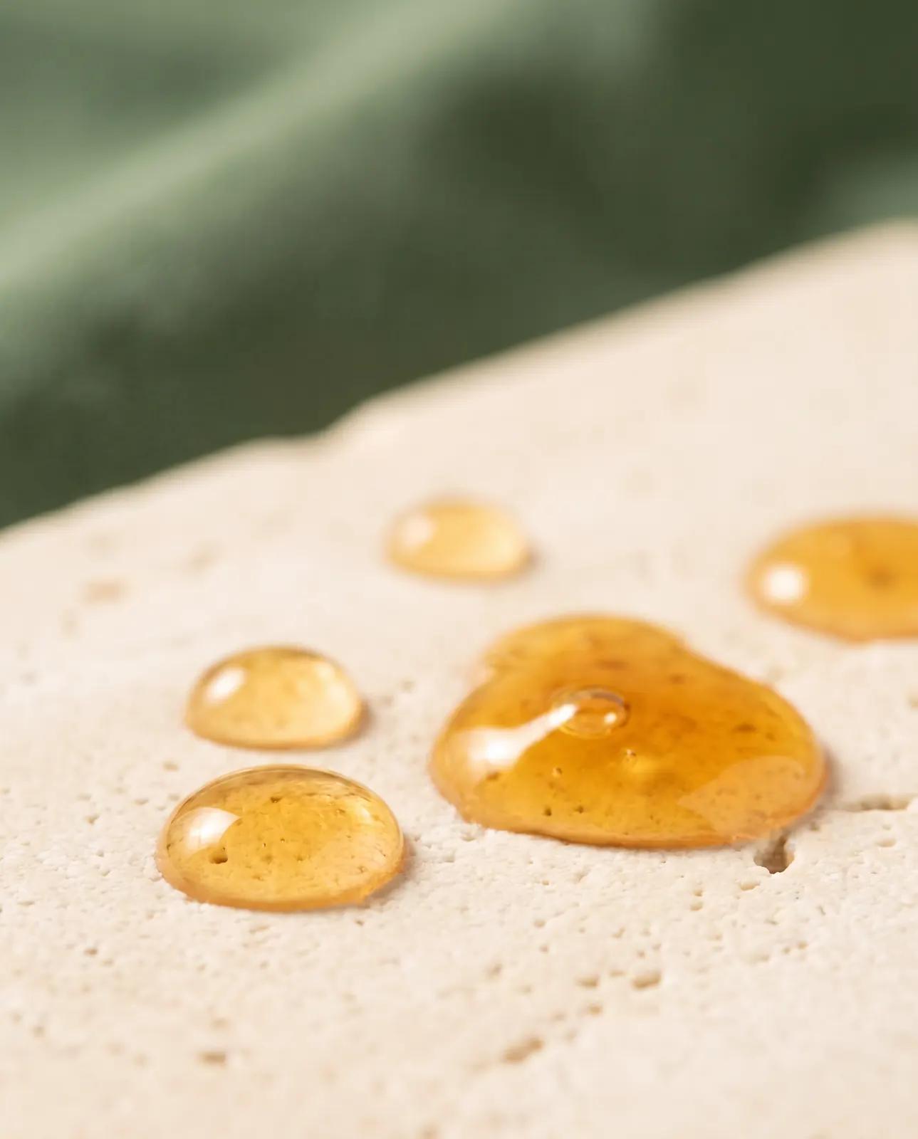 Gouttes dorées de collagène liquide sur une surface en pierre